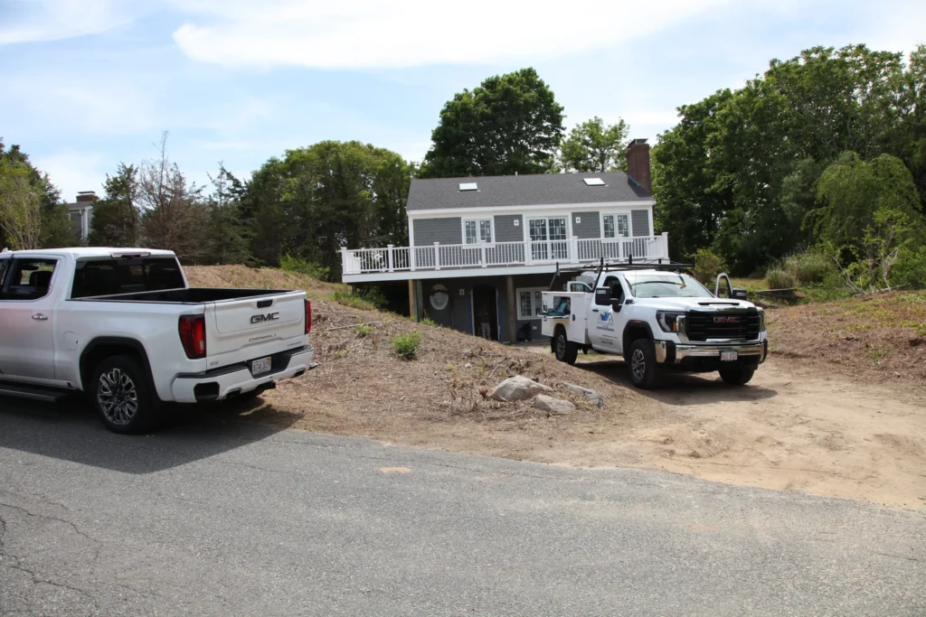 Custom Crafted Homes trucks outside a gray Cape home renovation in Dennis, MA