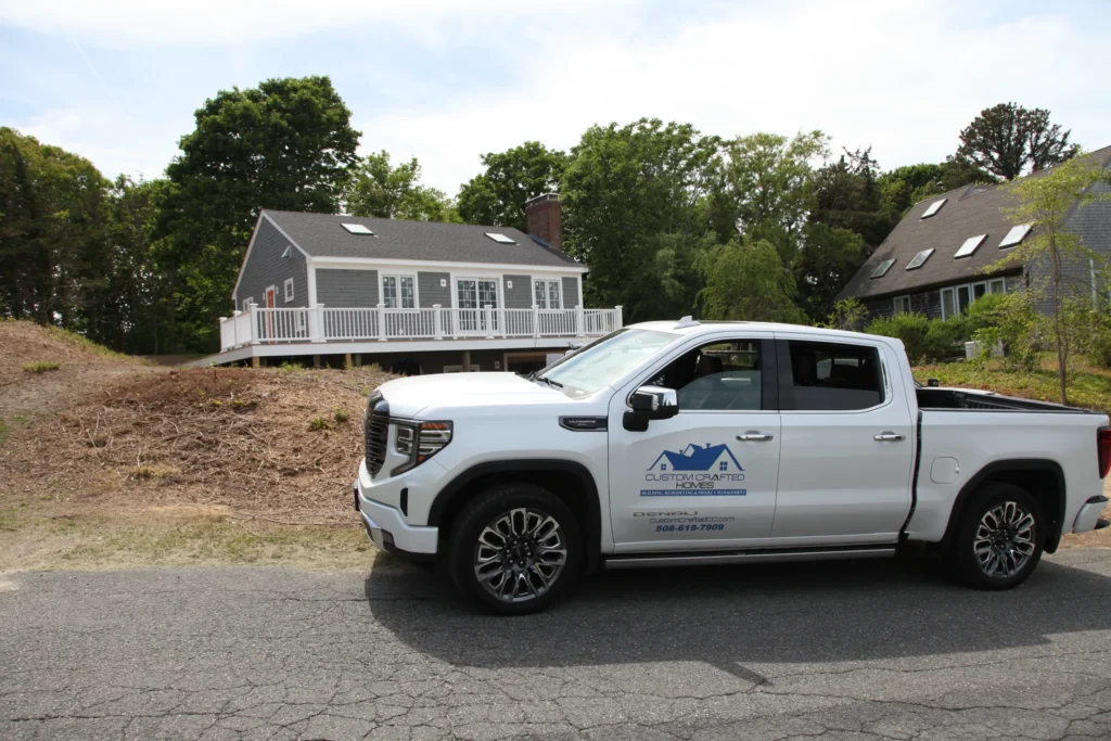 Custom Crafted Homes truck parked outside a gray Cape home in Dennis, MA