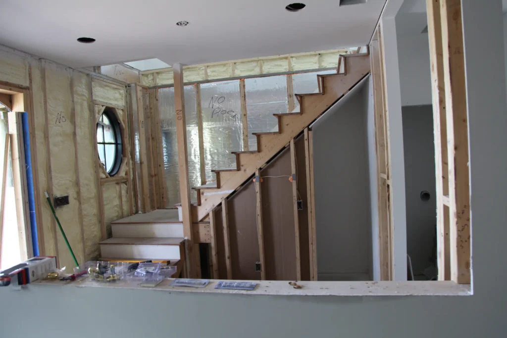 Interior stairway with exposed framing and insulation during a Dennis, MA renovation