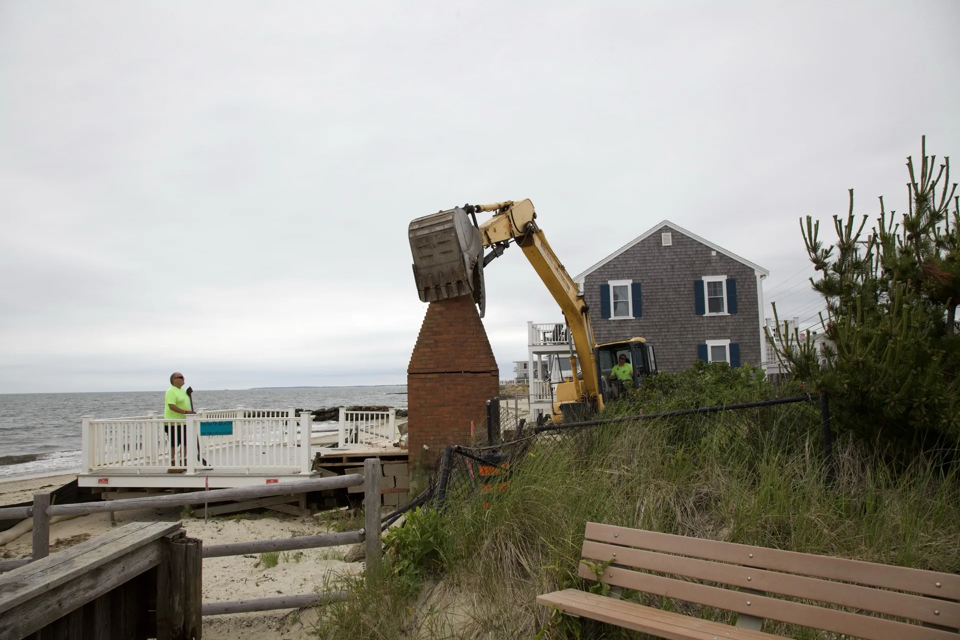 Crew member on the surviving deck watching the chimney come down, ocean and homes behind in Dennis Port.