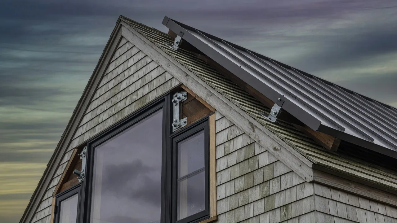 Storm-rated Cape Cod coastal home detail — impact-rated black-framed glazing and a standing-seam metal roof