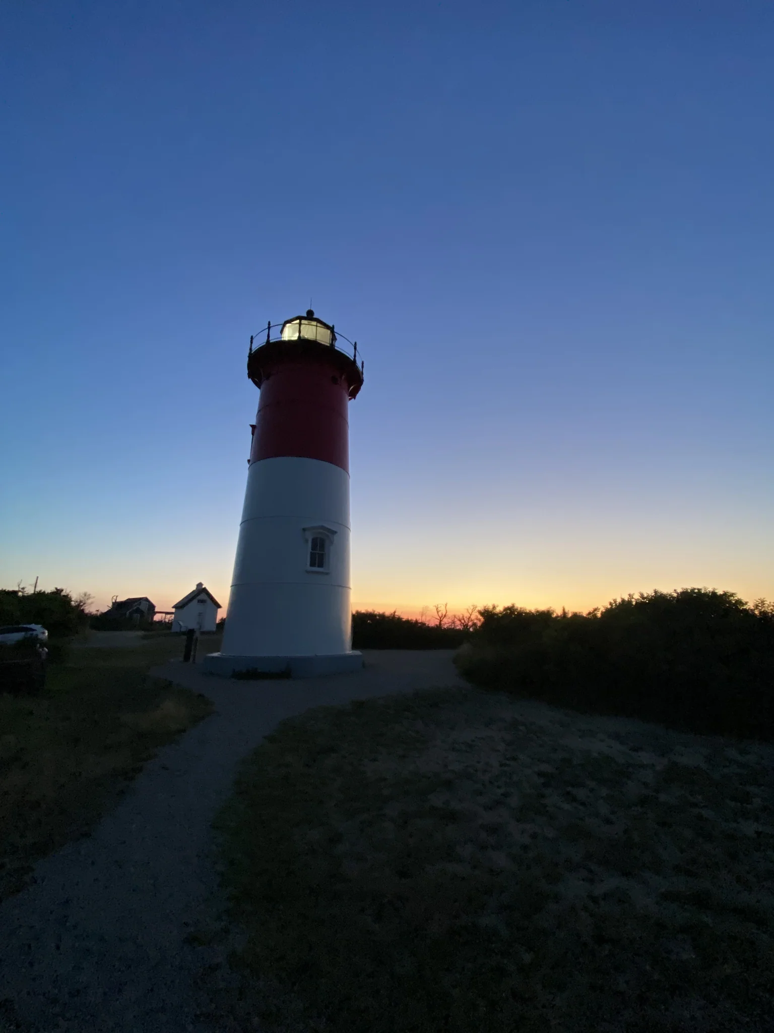 Nauset Light silhouetted against a dawn sky at the end of its path in Eastham