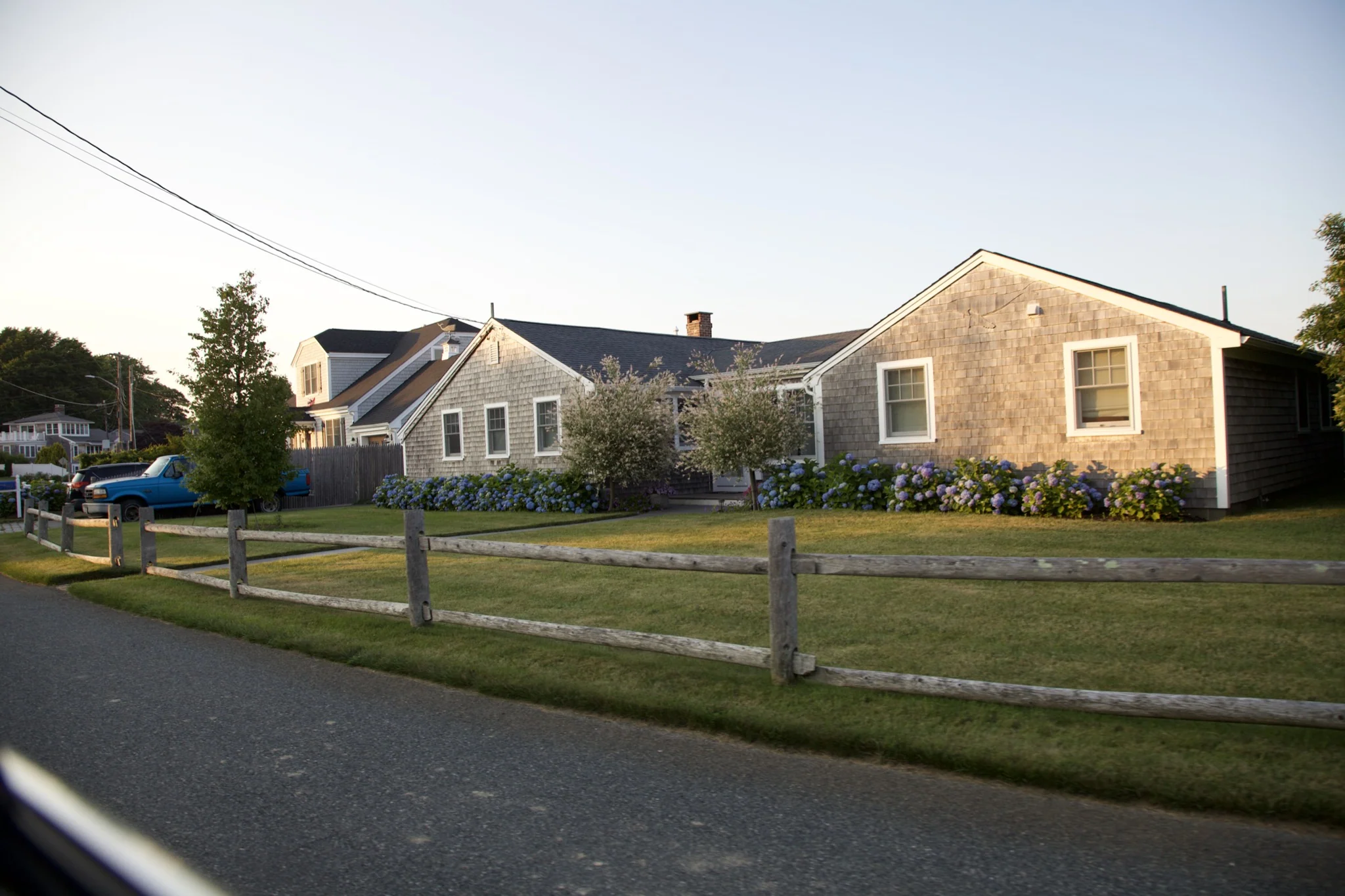 Cedar-shingle cottages set back behind lawn and fence in Hyannis Port