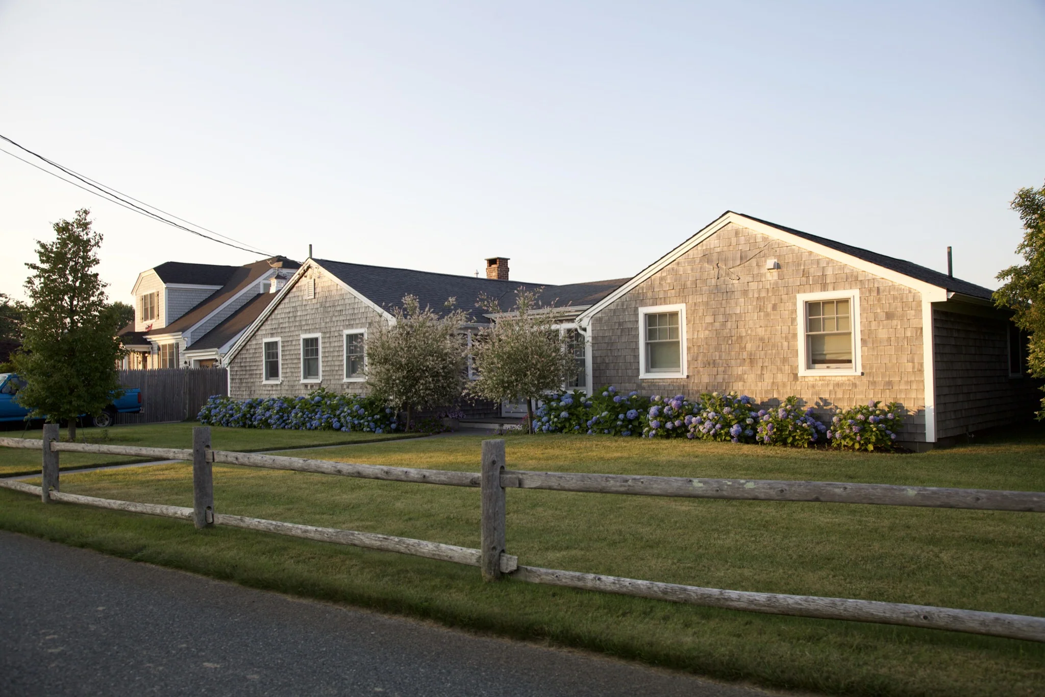 Row of cedar-shingle cottages behind a split-rail fence and hydrangea border in Hyannis Port