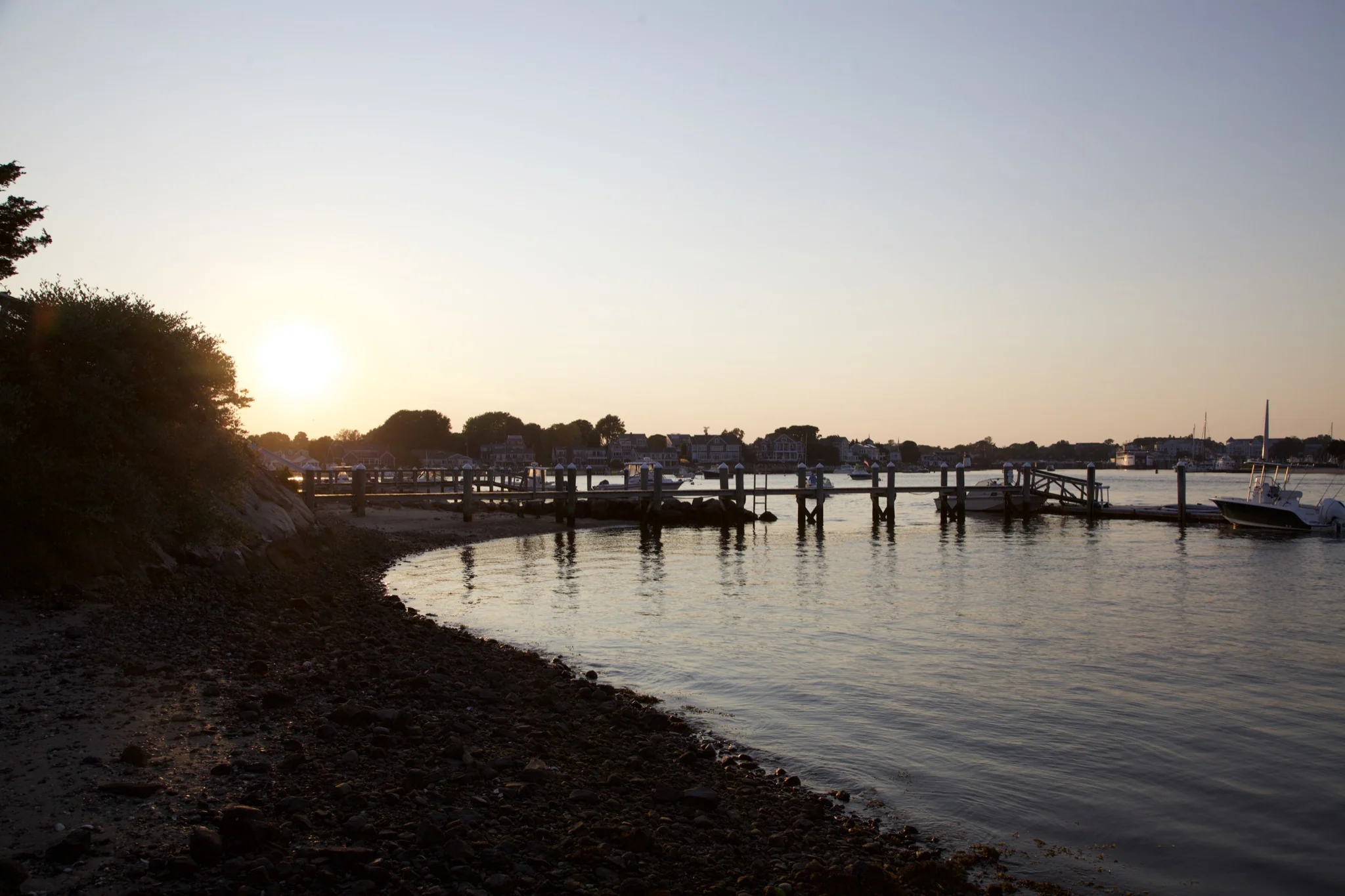 Hyannis Port harbor at golden hour with a wooden dock and moored boats