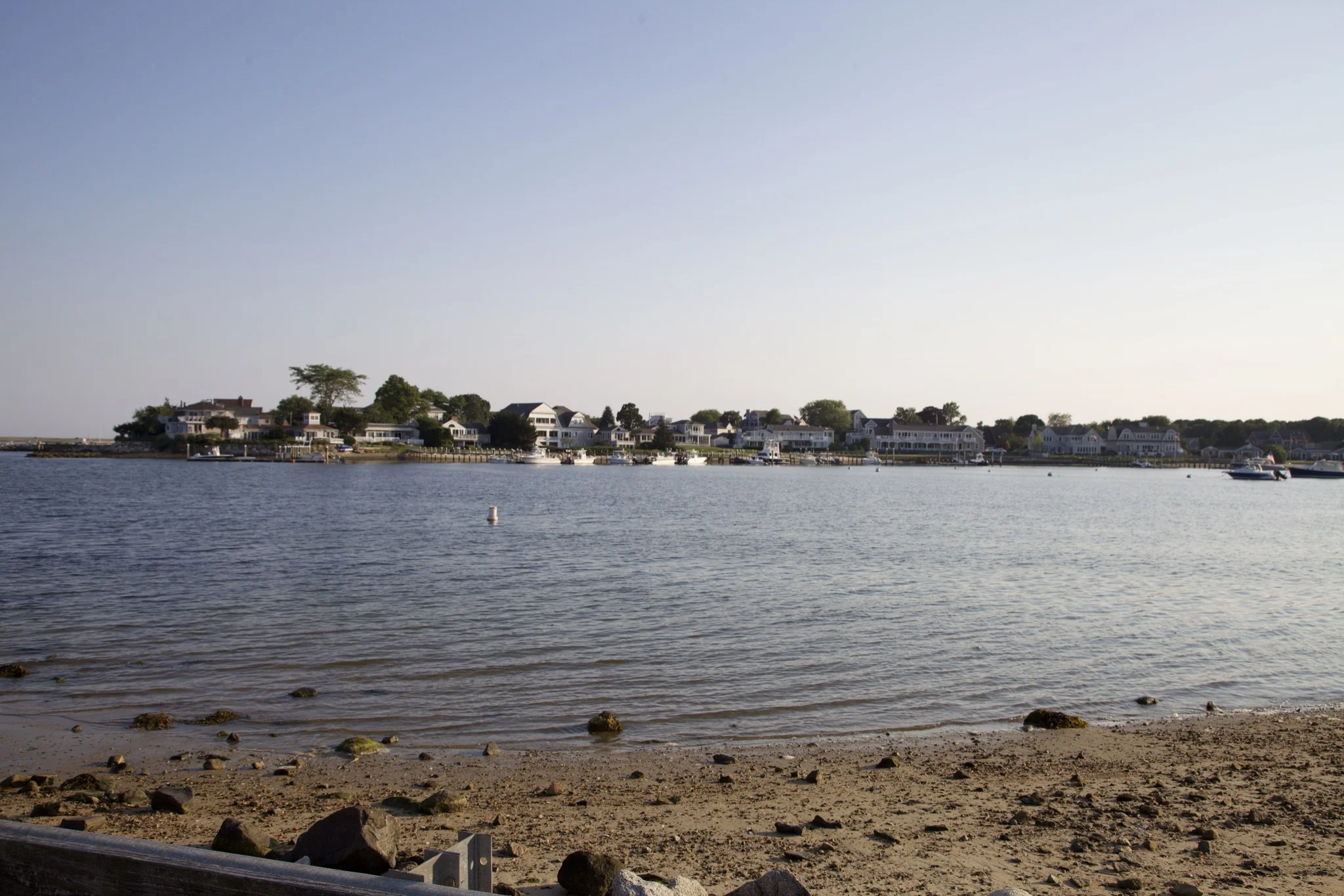 Shingled houses along the far shore of Hyannis Port harbor seen from the beach