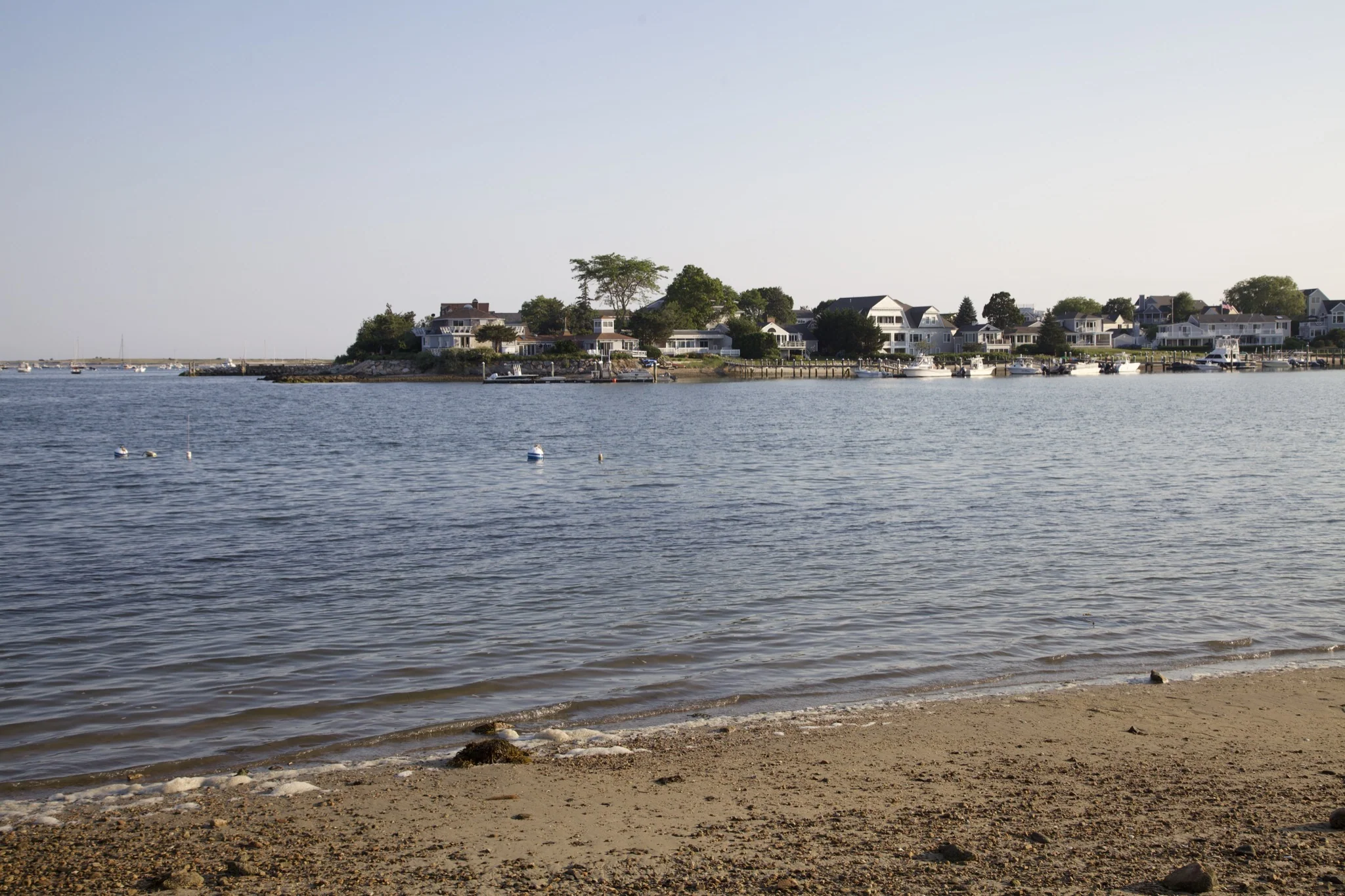 Shingled waterfront homes seen across the harbor from the beach in Hyannis Port