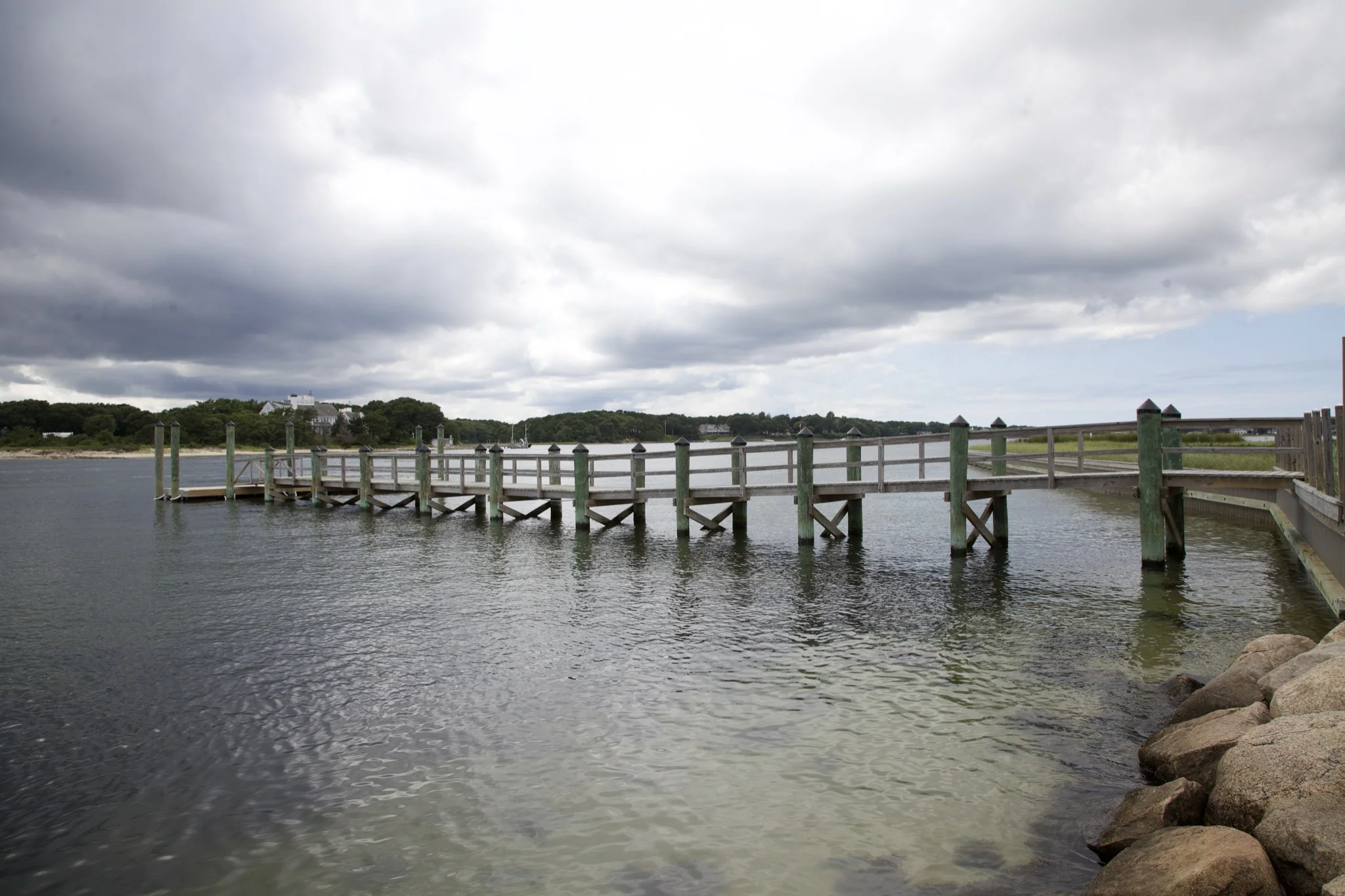 Long wooden dock on pilings reaching across the water at Osterville, Barnstable