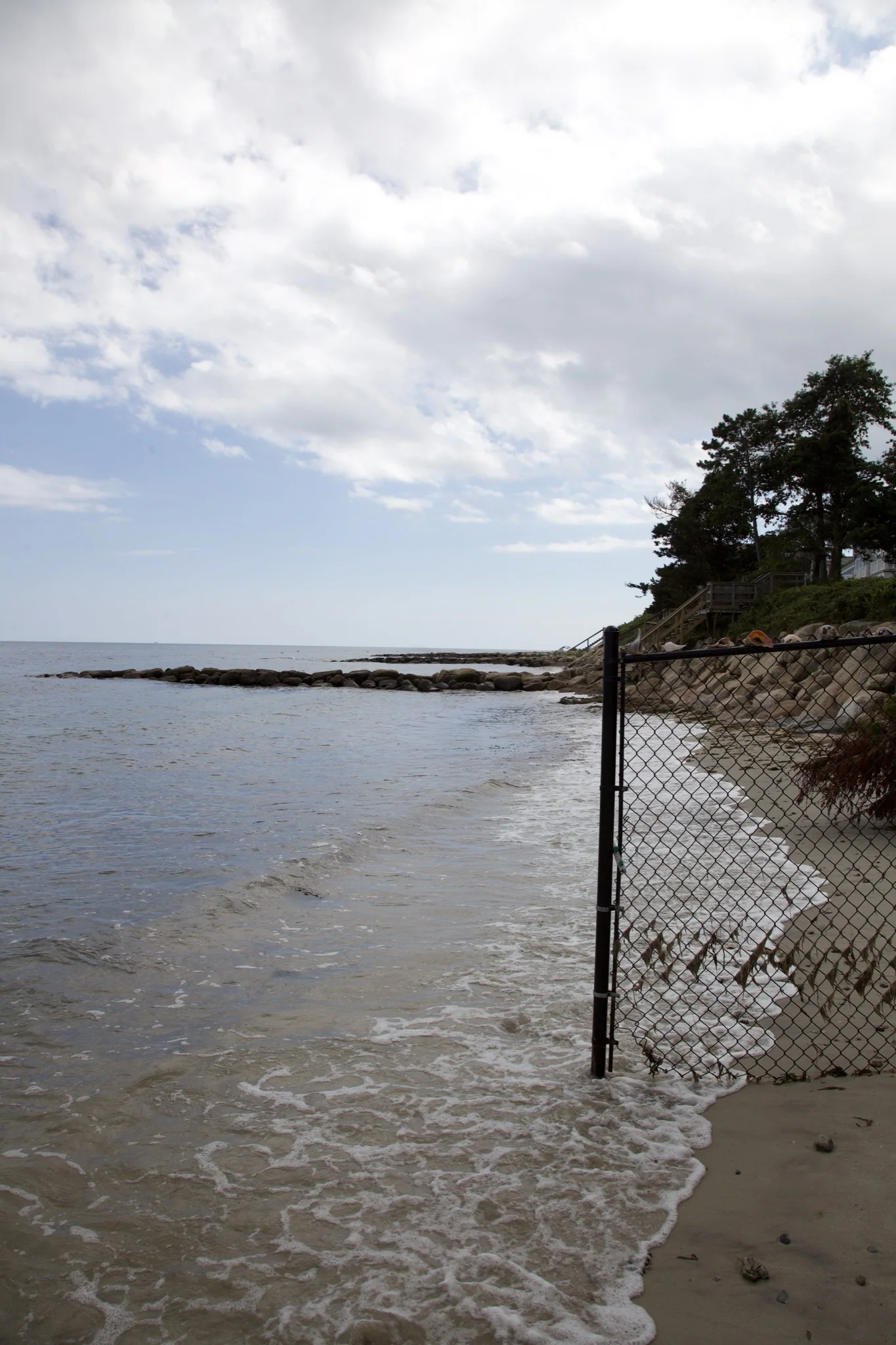 Tide running along the stone jetty and beach on the Osterville shoreline, Barnstable
