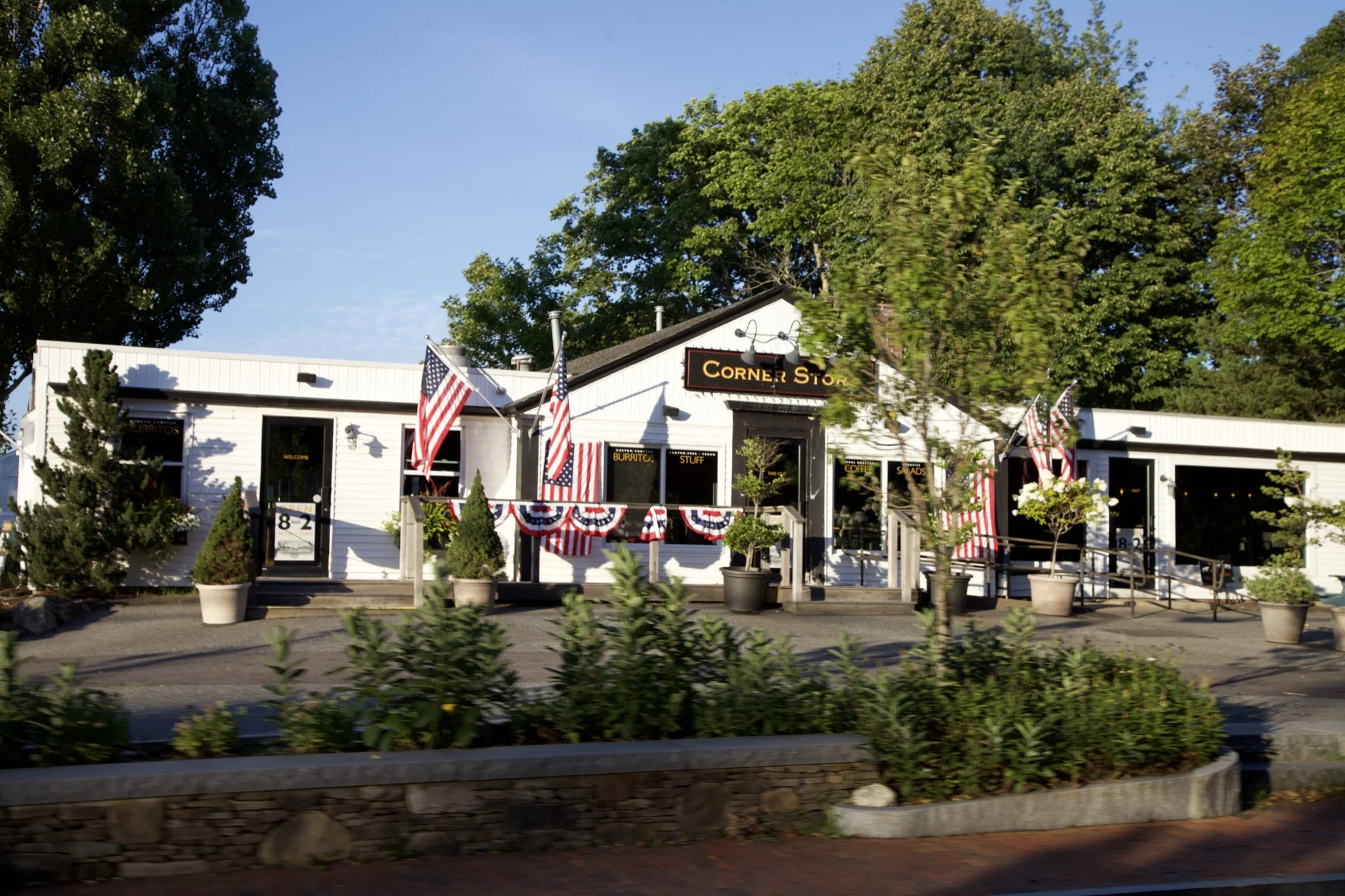 The Corner Store in Orleans, a white clapboard shop with American flags and bunting along its porch