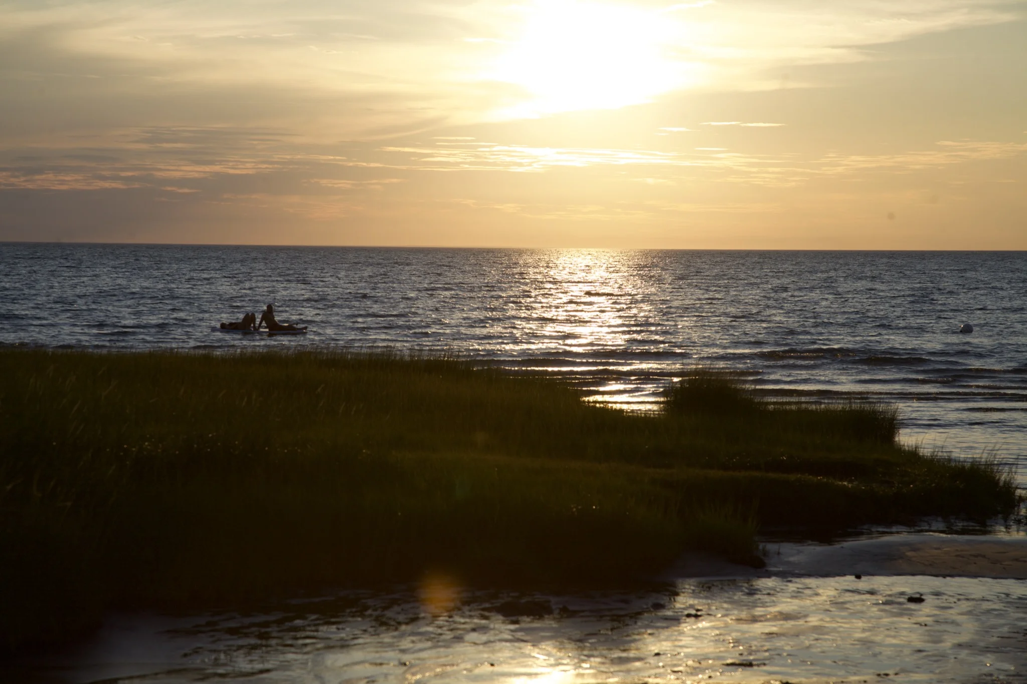 Two paddleboarders silhouetted on Cape Cod Bay at sunset off Skaket Beach in Orleans