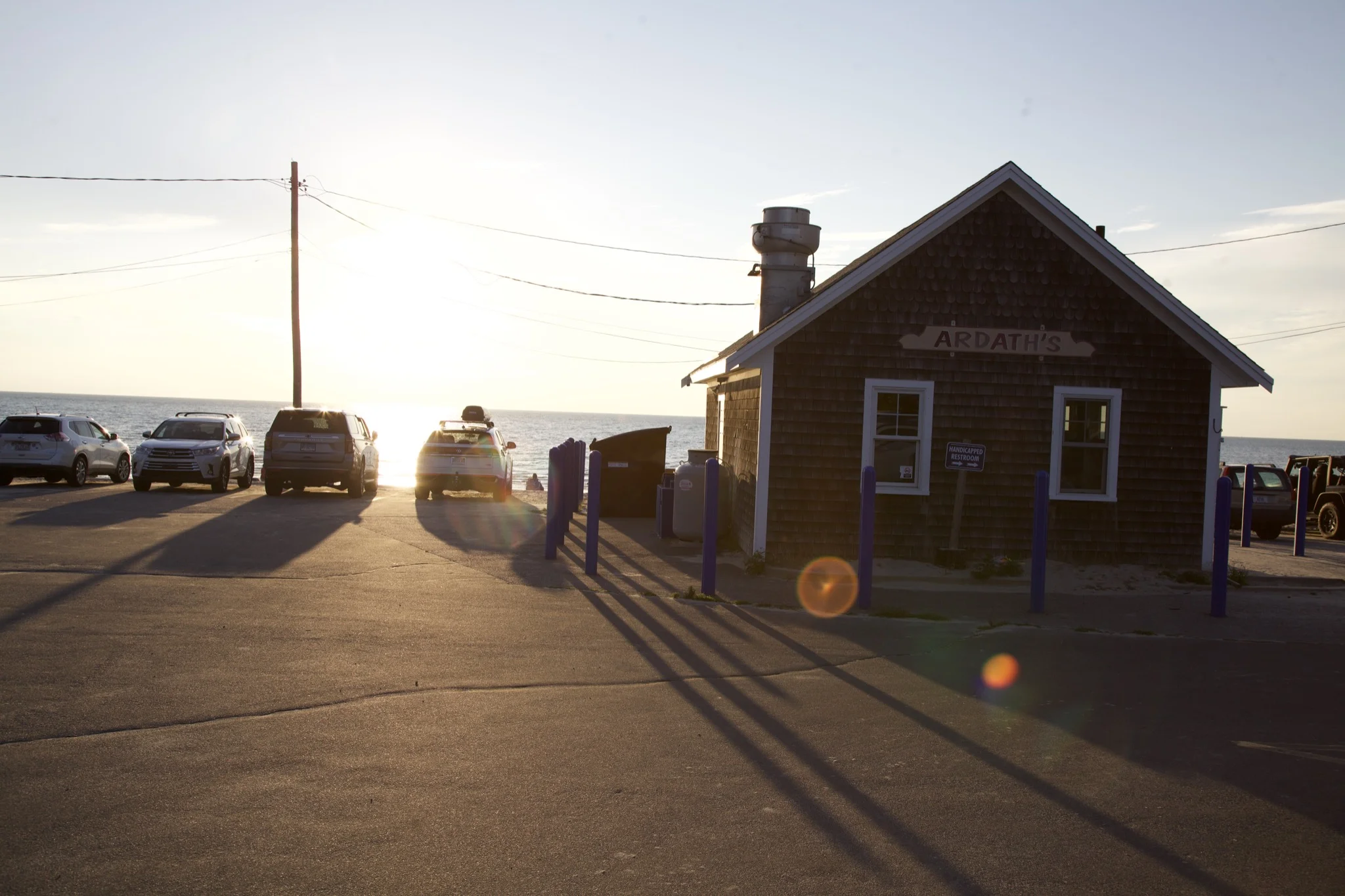 Ardath's, the weathered-shingle bathhouse at Skaket Beach in Orleans, with the sun low over Cape Cod Bay
